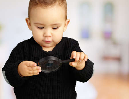Baby Boy looking at Magnifying Glass in his home