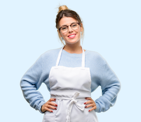 Young woman shop owner, wearing apron confident and happy with a big natural smile laughingの写真素材