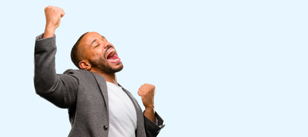 African american man with beard happy and excited celebrating victory expressing big success, power, energy and positive emotions. Celebrates new job joyful isolated over blue backgroundの写真素材