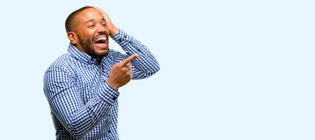 African american man with beard pointing away side with finger isolated over blue backgroundの写真素材