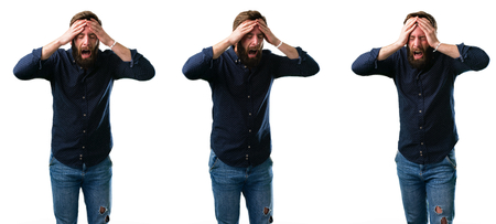 Young man with beard stressful keeping hands on head, terrified in panic, shouting isolated over white backgroundの写真素材