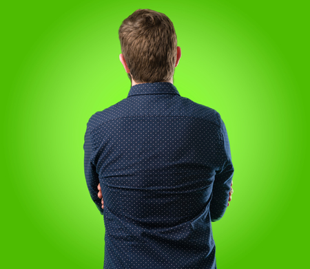 Young hipster man with big beard backside, rear view over green backgroundの写真素材