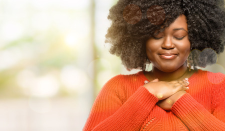Beautiful african woman with hands in heart, expressing love and health concept, outdoorの写真素材