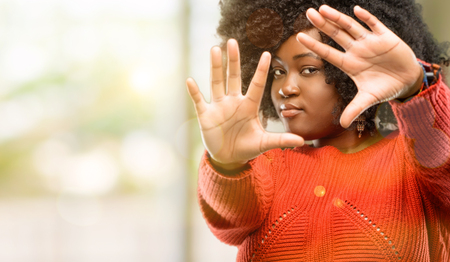 Beautiful african woman confident and happy showing hands to camera, composing and framing gesture, outdoorの写真素材