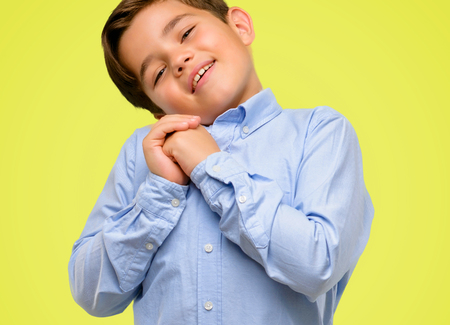 Handsome toddler child with green eyes confident and happy with a big natural smile laughing over yellow backgroundの写真素材