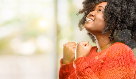 Beautiful african woman happy and excited celebrating victory expressing big success, power, energy and positive emotions. Celebrates new job joyful, outdoorの写真素材
