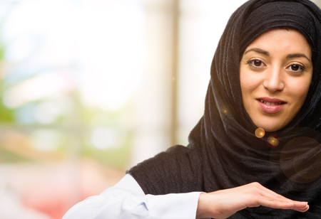 Young arab woman wearing hijab holding something, size conceptの写真素材