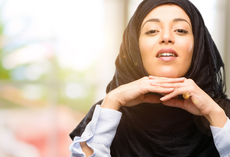 Young arab woman wearing hijab happy and surprised cheering expressing wow gestureの写真素材