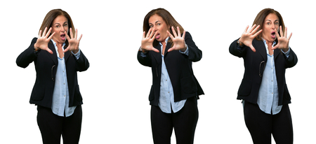 Middle age business woman disgusted and angry, keeping hands in stop gesture, as a defense, shouting over white backgroundの写真素材