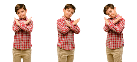 Handsome toddler child with green eyes annoyed with bad attitude making stop sign crossing hands, saying no, expressing security, defense or restrictionの写真素材