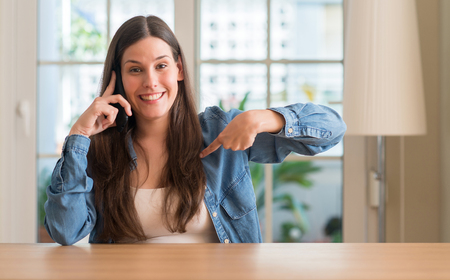 Young woman using smartphone with surprise face pointing finger to himselfの写真素材