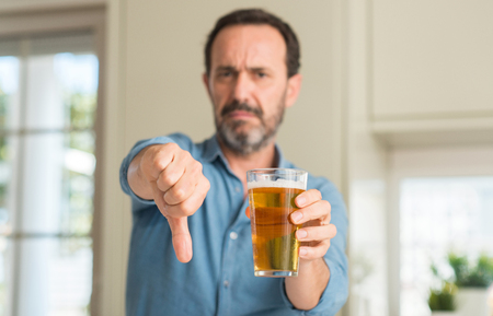 Middle age man drinking beer with angry face, negative sign showing dislike with thumbs down, rejection conceptの写真素材
