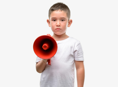 Dark haired little child holding megaphone with a confident expression on smart face thinking seriousの写真素材