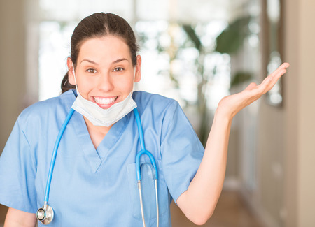Young nurse woman wearing mask and stethoscope very happy and excited, winner expression celebrating victory screaming with big smile and raised handsの写真素材