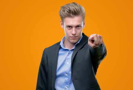 Young handsome blond business man pointing with finger to the camera and to you, hand sign, positive and confident gesture from the frontの写真素材