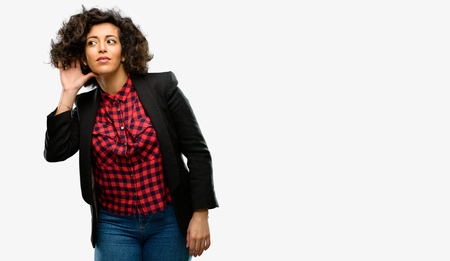 Beautiful arab woman holding hand near ear trying to listen to interesting news expressing communication concept and gossipの写真素材