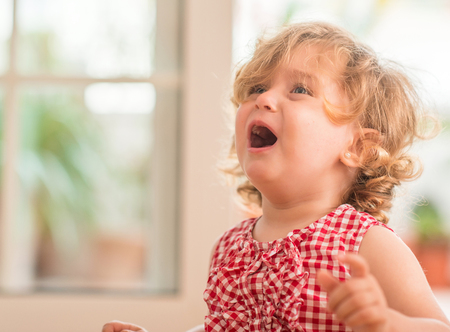 Beautiful blond child crying and shouting with tantrum at home.の写真素材