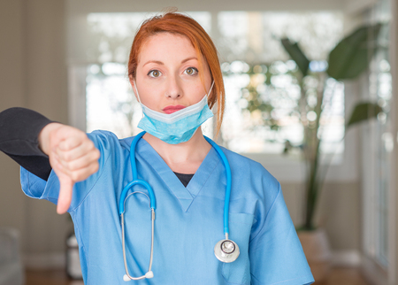 Medical professional woman with stethoscope with angry face, negative sign showing dislike with thumbs down, rejection conceptの写真素材