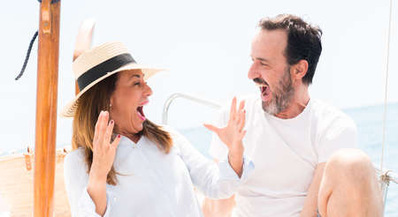 Middle age couple traveling on sailboat very happy and excited, winner expression celebrating...