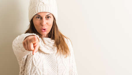 Middle age woman wearing wool winter cap pointing with finger to the camera and to you, hand sign, positive and confident gesture from the frontの写真素材