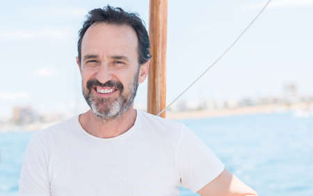 Handsome senior man traveling on sailboat and smiling happy and confident