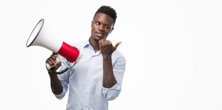 Young african american man holding megaphone pointing with hand and finger up with happy face smilingの写真素材