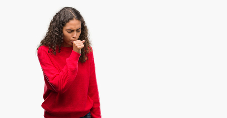 Young hispanic woman wearing red sweater feeling unwell and coughing as symptom for cold or bronchitis. Healthcare concept.の写真素材