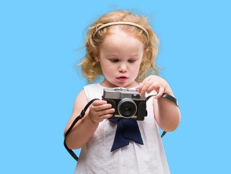 Beautiful blonde toddler taking pictures with vintage cameraの写真素材