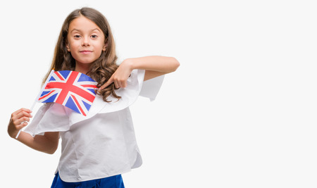 Brunette hispanic girl holding flag of United Kingdom with surprise face pointing finger to himselfの写真素材