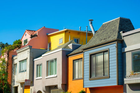 Row of modern colorful houses or homes in historic districts of san francisco california with clear blue sky and visible windows. Blue orange beige and white building facades in the city downtown.の写真素材