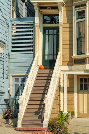 Dark timber framed door with long brown stairscase and white banister handrails in front of house in midday sub.の写真素材
