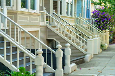 Red front door of home with glass pannel and white frame with beige paint on front porch with sign on top and red steps in foreground. In shade in afternoon in the neighborhood or on a house patio.の写真素材