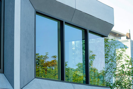 Metal chimney pipe on stucco gray and white exterior of house or home in shade and partial sun in late afternoon in the suburbs. In the urban neighborhood with blue sky background in the city.の写真素材