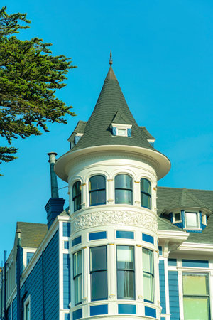 Metal saftey ladder on building or apartment complex with red or orange brick exterior with white stucco and decorative accent designs. Neighborhood in city or in suburbs in sun midday with blue skyの写真素材