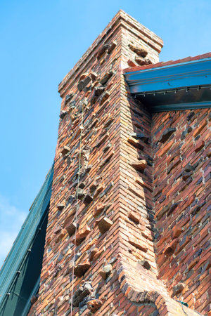 Metal fire escape balcony with rooftop access ladder on red stucco building with brown roof tiles on facade front of building. Blue sky background in midday sun in the city or urban area downtown.の写真素材
