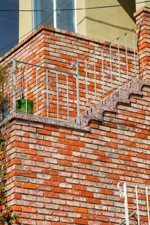 Close facade of brown wooden slatted timber building with white accent paint on window and near gable roof in midday sun. In the neighborhood or in a suburban part of the city or town.の写真素材