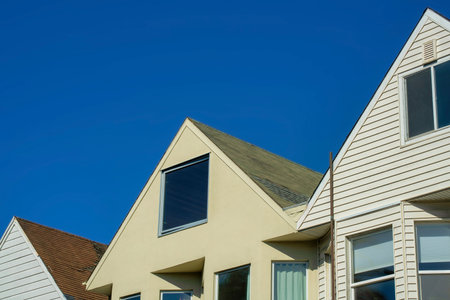 Close view of gray metal chimney pipes in sunset or twilight sun on side of building with wooden...