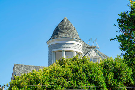 Blue turret or spire on house facade with wooden or timber pannel exterior with white accent decals and visible window with dark roof. In the neighborhood as detail shot of downtown neighborhood.の写真素材