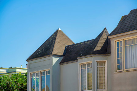 Blue turret or spire on house facade with wooden or timber pannel exterior with white accent decals and visible window with dark roof. In the neighborhood as detail shot of downtown neighborhood.の写真素材