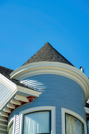 Blue turret or spire on house facade with wooden or timber pannel exterior with white accent decals and visible window with dark roof. In the neighborhood as detail shot of downtown neighborhood.の写真素材