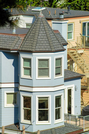 Row of modern houses in foreground with different colors and downtown city of san francisco california with skyscrappers. In afternoon sun with front yard trees and buildings in historic districts.の写真素材