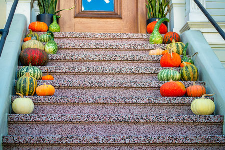 Red speckled cement stairs with decorative multicolored season festive squashes or pumpkins on porch or stoop near front door patio. In the neighborhood or on a house or home in the city.の写真素材