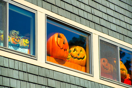 Holloween decorations in window with gray wooden building and white accent paint on holiday in the suburbs or city. In the neighborhood in october in the autumn for trick or treating in the downtown town.の写真素材