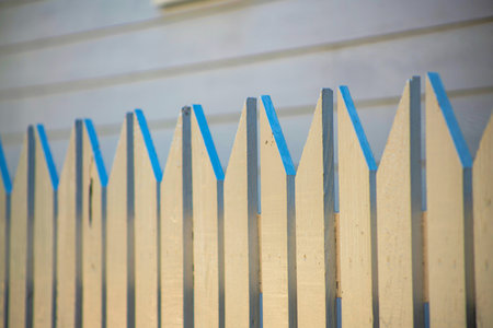 Late evening picket fence in a suburban area of the neighborhood or front yard in the downtown city. White wood planks and house or home exterior background in the garden.の写真素材