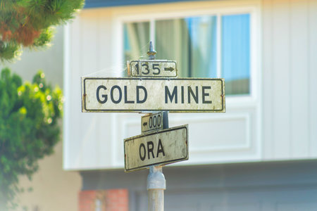 Road sign in suburban area that says gold mine. Street sign with white and black colored paint in shade in late afternoon.の写真素材