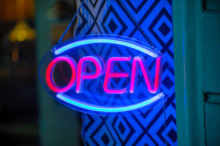 Neon sign with blue and red color that says open in the window of a shop or restaurant in the...
