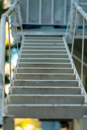 Metal access ladder on fire escape balcony for saftey and emergency in case of blaze or burning building. House in neighborhood or downtown city in modern urban area of suburbs.の写真素材