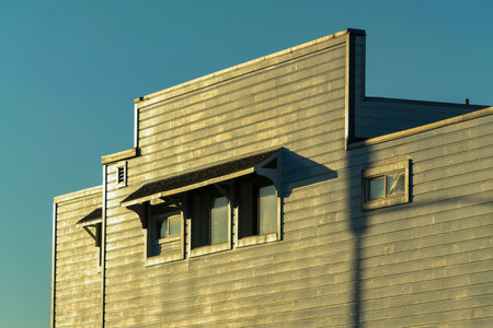 Urban building facade in sunset lighting with clear blue sky background in wild west style saloon or...