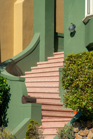 Decorative winding stairs on front porch of house with green stucco wall twisting up to front door of suburban houseの写真素材