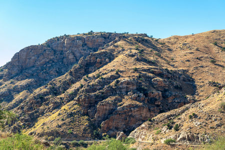 Rolling mountain hills with road and transportation in the cliffs and ridges of wild west great outdoors arizona. Shade and sunlight in afternoon sun in hiking and recreation areas.の写真素材